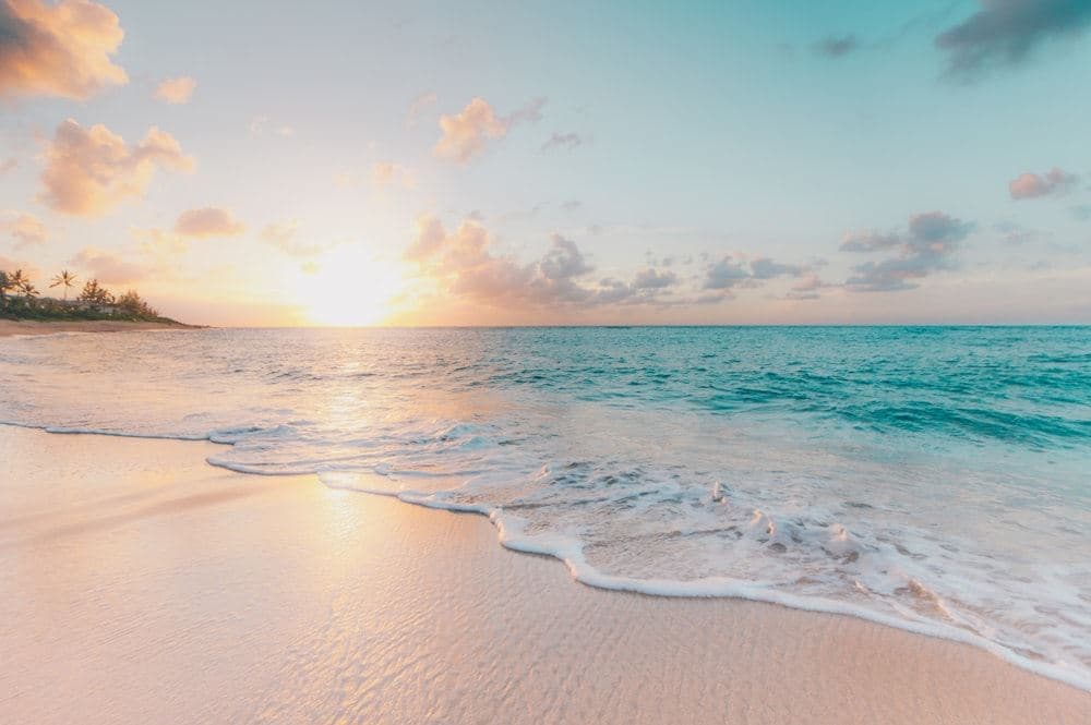 Soft sunset over a quiet Seychelles beach, gentle waves on pale sand